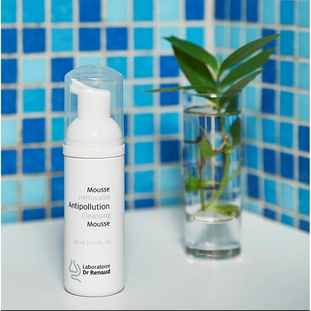 Antipollution Cleansing Mousse by Laboratoire Dr Renaud in pump bottle displayed on a bathroom surface with blue tiled background and a glass vase.