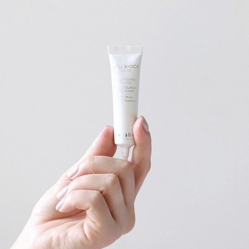 Hand holding Swissline Brightening Eye Veil SPF 50 tube close-up