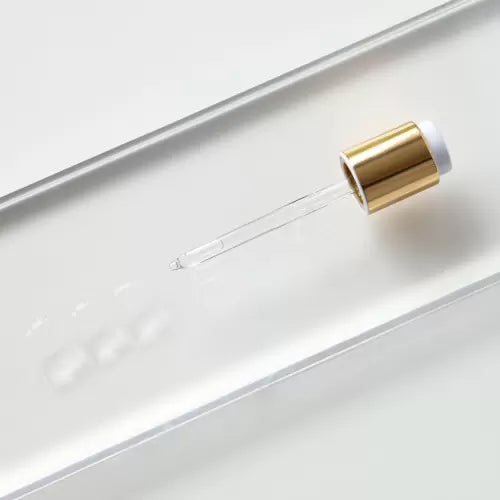 Eye serum dropper with clear liquid on glass surface