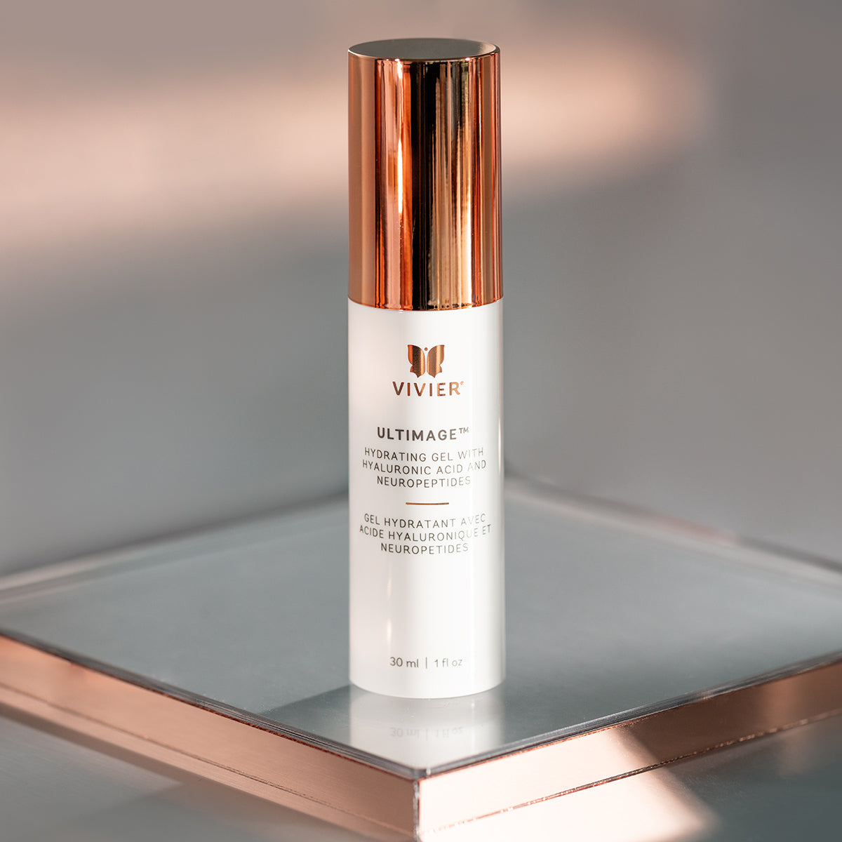 Vivier Ultimage hydrating serum bottle with gold cap displayed upright on a reflective surface